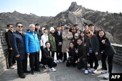 Former Taiwanese President Ma Ying-jeou (center right, wearing cap) poses for photographs with students at the Great Wall of China in the outskirts of Beijing on April 9, 2024. (Ma Ying-jeou Foundation via AFP)