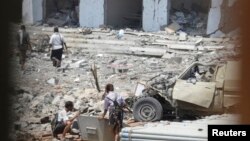 Soldiers are pictured through a window as they inspect the scene of a car bomb attack at a military police building in Mukallah city of the southern Yemeni province of Hadhramout May 11, 2014. A suicide car bomber killed six Yemeni army officers and wound