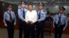 FILE - In this photo released by the Jinan Intermediate People's Court, fallen politician Bo Xilai, center, is handcuffed and held by police officers as he stands at the court in Jinan, in eastern China's Shandong province, Sept. 22, 2013. 