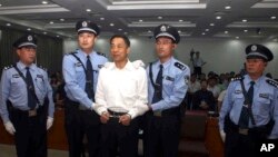 FILE - In this photo released by the Jinan Intermediate People's Court, fallen politician Bo Xilai, center, is handcuffed and held by police officers as he stands at the court in Jinan, in eastern China's Shandong province, Sept. 22, 2013. 