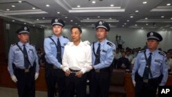 FILE - In this photo released by the Jinan Intermediate People's Court, fallen politician Bo Xilai, center, is handcuffed and held by police officers as he stands at the court in Jinan, in eastern China's Shandong province, Sept. 22, 2013. 