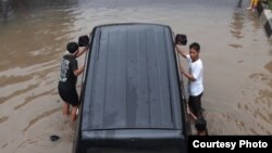 Warga mendorong mobil yang mogok terendam banjir di Karawang, Jawa Barat. (Foto: Dok)