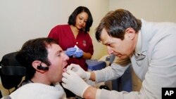 Jason DiSanto mendapat tindikan di lidah di Georgia Tech di Atlanta, untuk memasukan alat seperti perhiasan yang dapat mengendalikan kursi rodanya. (AP/Georgia Tech) 