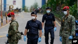 FILE - Military and police stand guard with protective face masks enforcing a coronavirus lockdown order, in Kuala Lumpur, Malaysia, March 31, 2020.