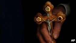 FILE —An Orthodox Christian worshipper holds a cross during a Good Friday procession at the Church of the Holy Sepulcher, where many Christians believe Jesus was crucified, buried and rose from the dead, in Jerusalem's Old City, Friday, April 14, 2023. 