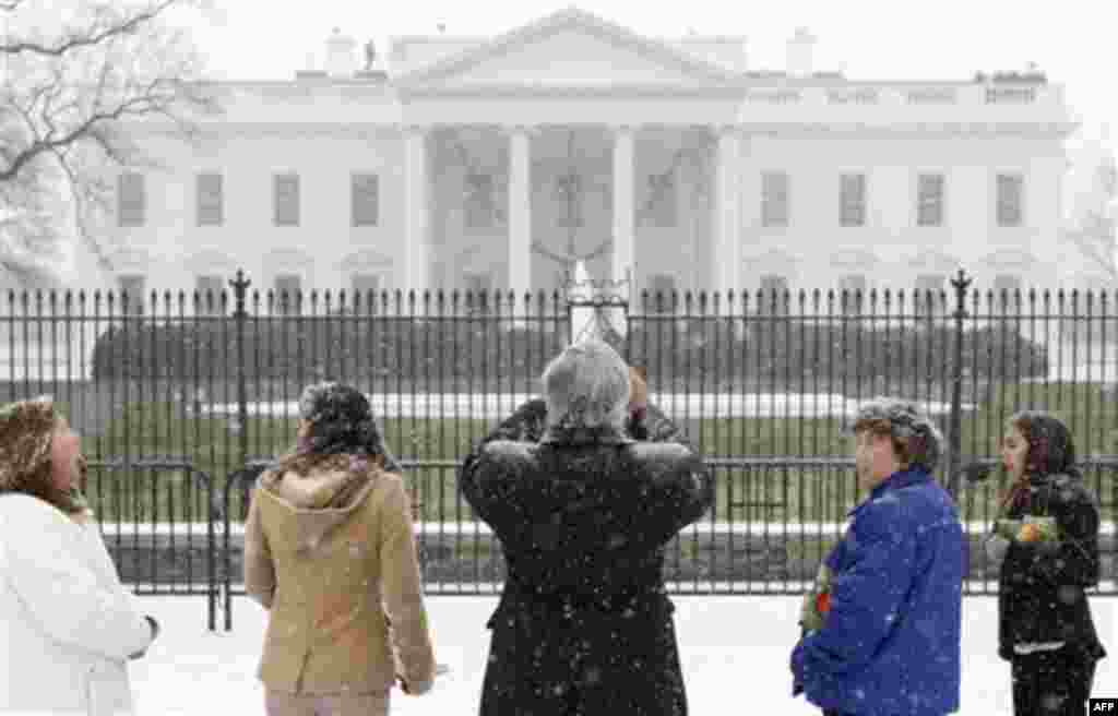 Visitors stop to take photographs of the White House as snow falls in Washington, Thursday, Dec. 16, 2010. (AP Photo/Charles Dharapak)