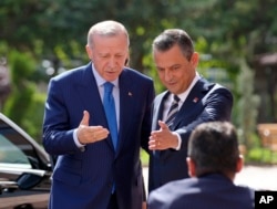 FILE - Turkish President Recep Tayyip Erdogan, left, and Ozgur Ozel, leader of main opposition Republican People's Party, gesture as Erdogan arrives for a meeting in Ankara, June 11, 2024.