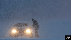 A man gets into a vehicle on a snowbank on the exit to a business along Route 23 during a snowstorm, Wednesday, March 7, 2018, in Wayne, N.J. 
