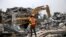 An emergency official watches an excavator dig through the rubble of a collapsed building in the Victoria Island district of Lagos on November 5, 2013. 