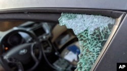 FILE - A parked car with a broken front window after a smash-and-grab break-in in Los Angeles. 