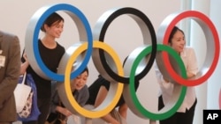 People pose for photo with the Olympics Rings display at Haneda International Airport in Tokyo, Thursday, July 8, 2021. (AP Photo/Koji Sasahara)