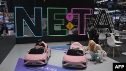 FILE - People play with mini cars in front of a booth for Chinese electric vehicle (EV) manufacturer Neta at the Bangkok International Motor Show in Nonthaburi on March 27, 2024.