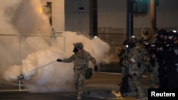 A federal law enforcement officer, deployed under the Trump administration's new executive order to protect federal monuments and buildings, uses tear gas during a protest over racial inequality in Portland, Oregon, July 17, 2020.