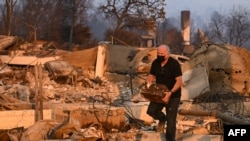 A resident recovers a safe from their home after it was destroyed during the Palisades Fire in Pacific Palisades, a neighborhood of Los Angeles, California, on January 9, 2025.