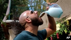 In this Sept. 8, 2018 photo, a Lebanese man drinks arak from a traditional glass pitcher during a festival that celebrates Lebanon's national alcoholic drink, in the town of Taanayel, east Lebanon. 