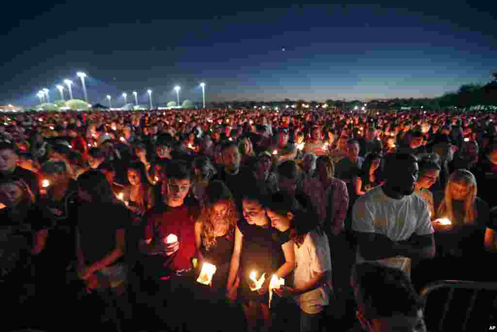 People attend a candlelight vigil for the victims of the Wednesday shooting at Marjory Stoneman Douglas High School, in Parkland, Fla.