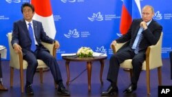 Russian President Vladimir Putin, right, and Japanese Prime Minister Shinzo Abe pose for a photo during their meeting in Vladivostok, Russia, Sept. 2, 2016. 