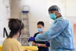 FILE - A healthcare worker prepares to conduct a COVID-19 test on a patient at a testing facility in Melbourne, Australia, Aug. 20, 2020. (AAP Image/James Ross via Reuters)