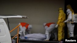 Trabajadores de funerarias extraen el cuerpo de un hombre que murió frente a una clínica, mientras continúa el brote de la COVID-19, en San Salvador, el 2 de julio de 2020.