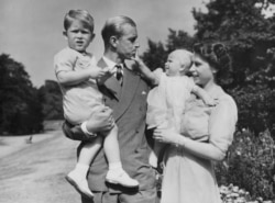 FILE - In this Aug. 1951 photo, Britain's Queen Elizabeth II, then Princess Elizabeth, stands with her husband, Prince Philip, the Duke of Edinburgh, and their children Prince Charles and Princess Anne at Clarence House.