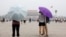 Pengunjung ke Lapangan Tiananmen melindungi diri dari matahari dengan payung di hari yang panas dan berkabut di Beijing. (Foto: Reuters)