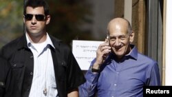 Former Israeli Prime Minister Ehud Olmert (R) speaks on the phone as he leaves the Jerusalem District court, September 24, 2012.