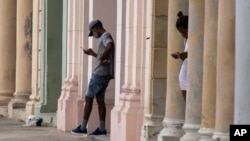 Dos personas consultan sus celulares en el malecón de La Habana, el 14 de julio de 2021.