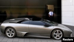 A police officer stands near a 2007 Lamborghini Murcielago, part of a group of vehicles seized by the government from politicians and organized crime as part of an auction in Mexico City, May 21, 2019. 