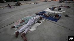 Radnici spavaju na cesti tokom ranog vrućeg jutra u Karačiju, Pakistan, srijeda, 29. maja 2024.