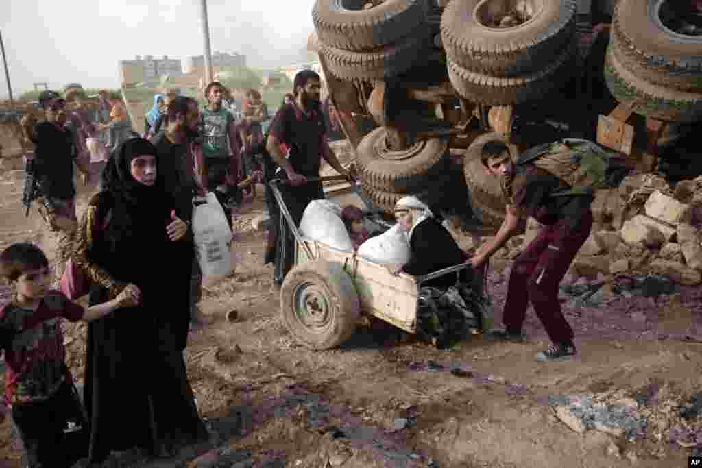 Dua pria berusaha menarik kereta yang berisi seorang perempuan lansia dan anak balita, sementara warga sipil mengungsi untuk menghindari peperangan pasukan Irak dan militan ISIS di Mosul barat, Irak.