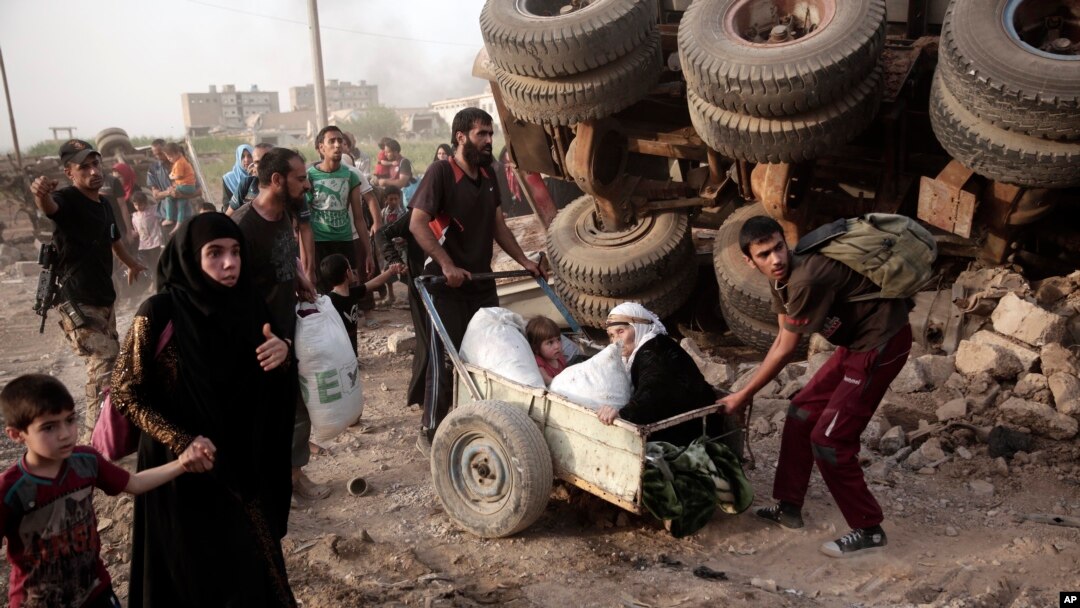 FILE - An elderly woman and a child are pulled on a cart as civilians flee heavy fighting between Islamic State militants and Iraqi special forces in western Mosul, Iraq, May 10, 2017.