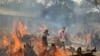 Relatives react to heat emitting from the multiple funeral pyres of COVID-19 victims at a crematorium in the outskirts of New Delhi, India, Apr. 29, 2021. 