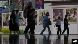 2026年8月17日，北京一家高档露天购物中心，购物者走过展示的时尚海报。