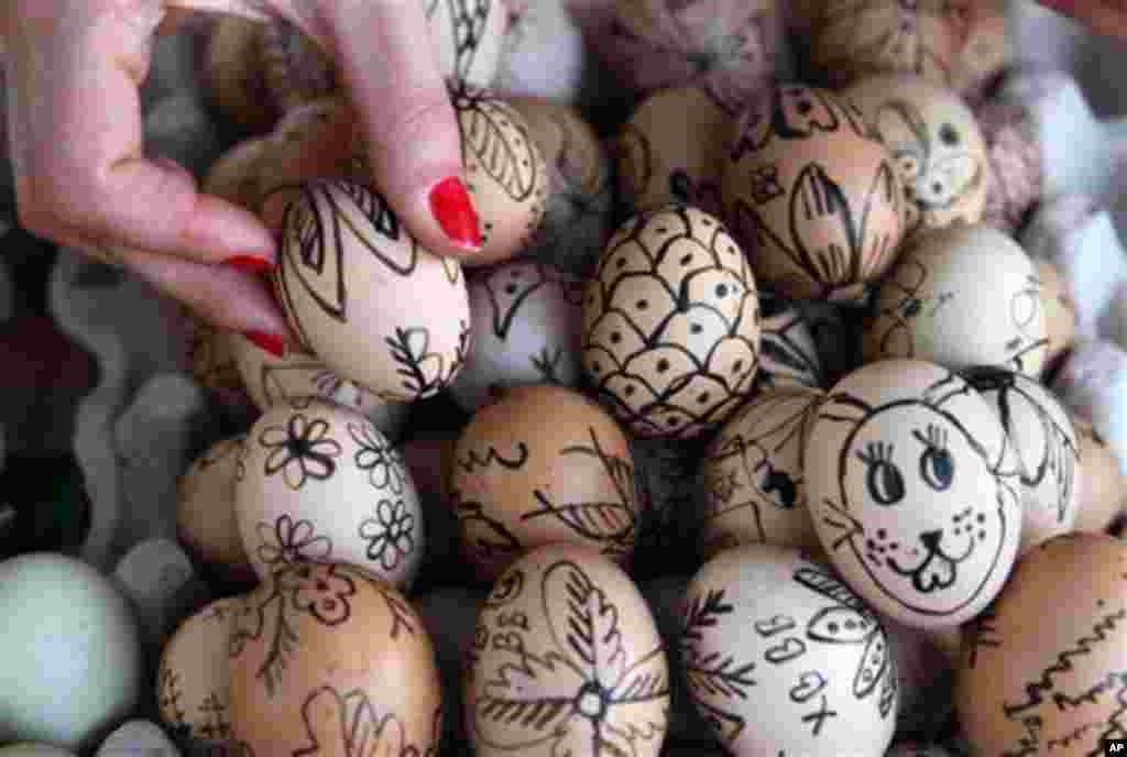 A buyer selects from the pile of hand-decorated Easter eggs at the green market, in Belgrade, Serbia, on Orthodox holy Thursday, on Thursday May 2, 2013. Orthodox Serbs celebrate Easter on May 5, according to old Julian calendar.(AP Photo/Darko Vojinovic)