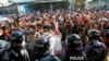 Residents and protesters face riot police as they question them about recent arrests made in Mandalay, Myanmar, Feb. 13, 2021. 