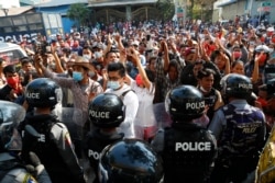 FILE - Residents and protesters face riot police as they question them about recent arrests made in Mandalay, Myanmar, Feb. 13, 2021.