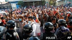 Residents and protesters face riot police as they question them about recent arrests made in Mandalay, Myanmar, Feb. 13, 2021. 