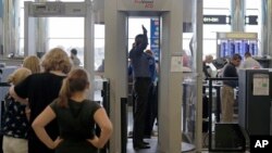 FILE - Passengers are scanned at a Terminal C security checkpoint at Logan Airport in Boston using a millimeter wave body scanner. 