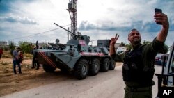 Un miembro de Asayish, o las Fuerzas de Seguridad Interna, hace una selfie junto a un vehículo militar ruso, durante una patrulla cerca de la frontera siria y turca, en el norte de Siria, el viernes. 