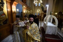 Greek Orthodox priests hold aloft the bier depicting Christ's preparation for burial during the Good Friday procession of the Epitaphios, held in an empty church in Thessaloniki, Greece, April 17, 2020.