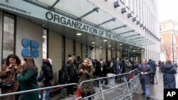 FILE - People stand in front of the headquarters of the Organization of the Petroleum Exporting Countries (OPEC) in Vienna, Austria, March 6, 2020.