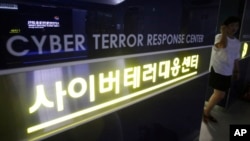 FILE - A woman walks by a sign at Cyber Terror Response Center of National Police Agency in Seoul, South Korea. 