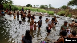 Migrantes que viajan en caravana para llegar a la frontera de Estados Unidos a través de México se bañan en un río, en Mapastepec, México, 29 de diciembre de 2023.