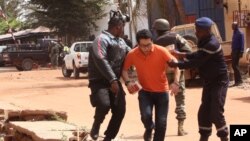 Mali troopers assist a hostage, centre, to leave the scene, from the Radisson Blu hotel to safety after gunmen attacked the hotel in Bamako, Mali, Friday, Nov. 20, 2015. 