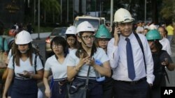 Oficinistas usando cascos desalojan el edificio donde trabajan después de un sismo de magnitud 6,1 en Manila, Filipinas, el 22 de abril de 2019. (AP Foto/Aaron Favila)