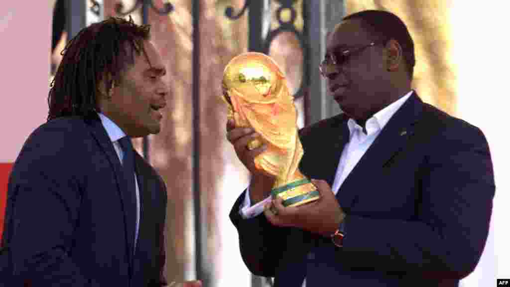 L&#39;ancien footballeur international français Christian Karembeu présente le trophée de la Coupe du monde au président sénégalais Macky Sall lors d&#39;une cérémonie à Dakar, le 11 mars 2018.