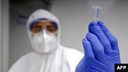 Un trabajador de salud muestra una prueba de PCR para la detección de COVID-19 en el laboratorio del Centro Universitario de Ciencias de la Salud (CUCS) en Guadalajara, estado de Jalisco, México, el 14 de abril de 2021.