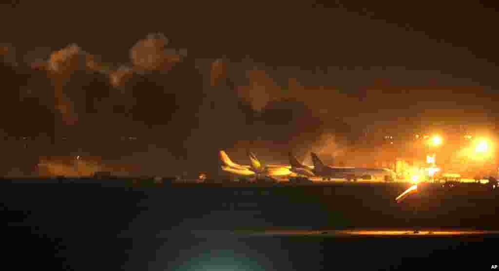 Fire illuminates the sky above the Jinnah International Airport in Karachi, Pakistan, June 8, 2014. Gunmen disguised as police guards attacked a terminal with machine guns and a rocket launcher during a five-hour siege that killed 28 people as explosions echoed into the night, while security forces retaliated and killed all the attackers, officials said.