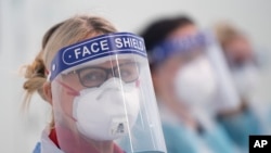 In this April 16, 2020, photo, medical staff receive training on how to use personal protective equipment to avoid coronavirus transmission in Manchester, northern England.