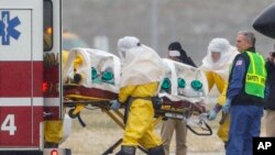 Health workers in protective suits transport Dr. Martin Salia, a surgeon working in Sierra Leone who had been diagnosed with Ebola, at Nebraska Medical Center in Omaha, Neb., Nov. 15, 2014. 